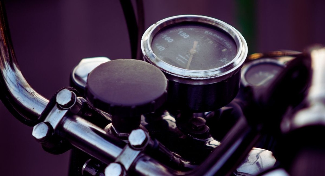 Gros plan sur le compteur kilométrique et le guidon chromé d'une moto classique