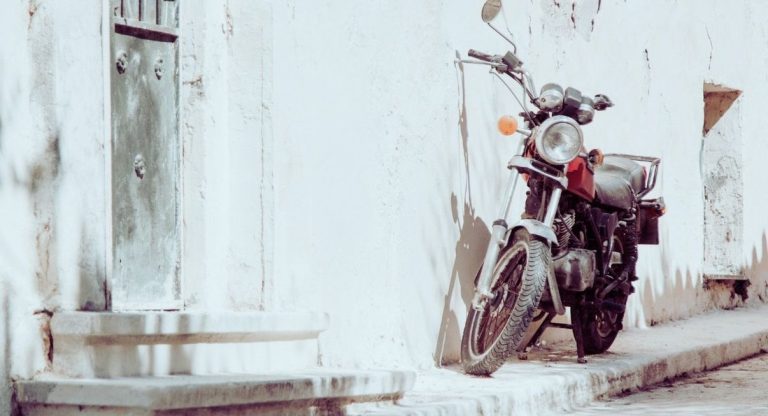 Moto des années 80 garée sur un trottoir contre un mur blanchi à la chaux