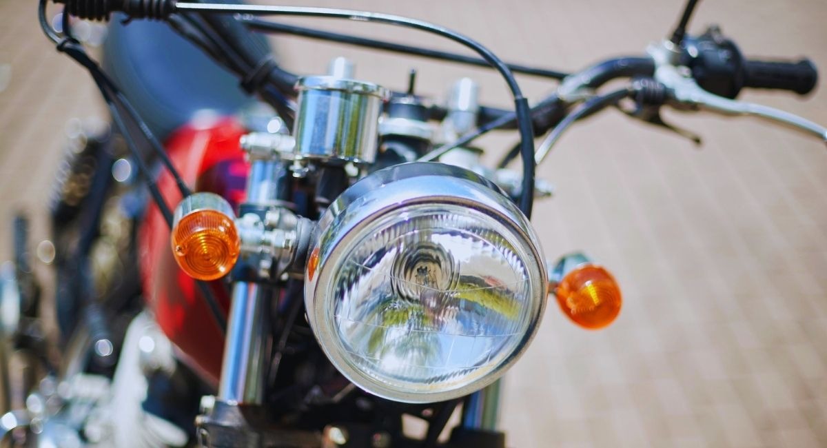 Phare rond chromé et clignotants orange à l'avant d'une moto classique